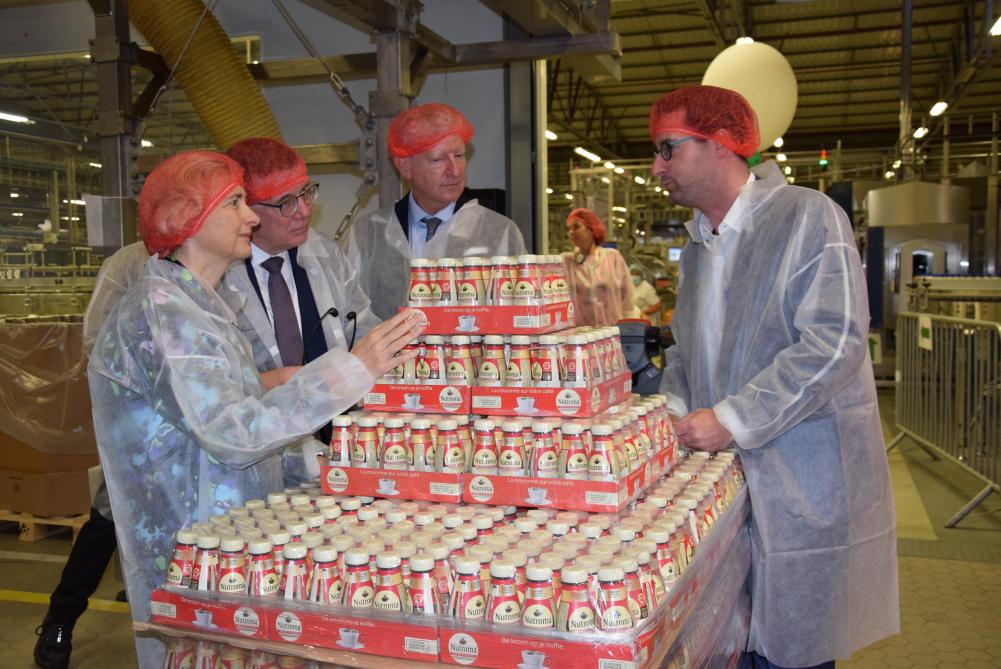 Jeroen Van de Broek (rechts) beschrijft tijdens de rondgang doorheen het bedrijf het innovatieve Nutroma-flesje aan minister Crevits, Hans Maertens van Voka en burgemeester Pieter De Crem.