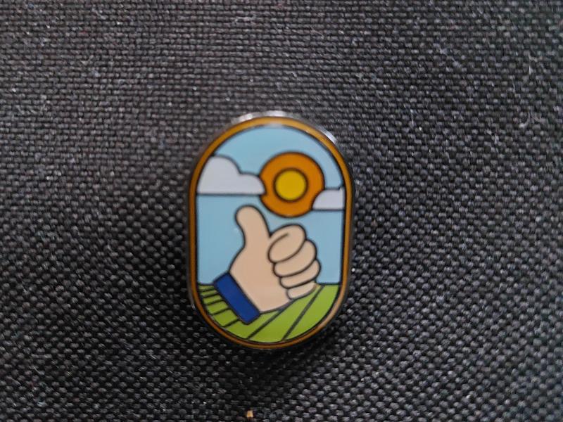 Een pin duidt op solidariteit met de lokale landbouw. De achterliggende slogan is ‘Jouw sympathie geeft onze boeren energie’.