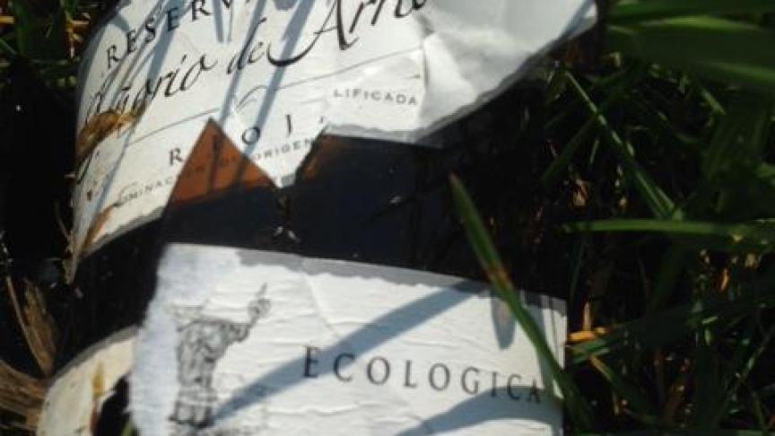 Een fles ecologisch wijn, op niet zo’n ecologische manier gedumpt in een weide.