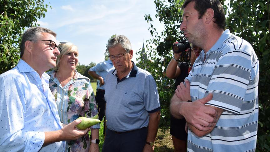 Minister Koen Van den Heuvel, Europarlementariër Hilde Vautmans en burgemeester Stefaan Devos luisteren naar fruitteler Luc Borgugnons.