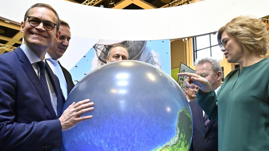 De Duitse landbouwminister Julia Kloeckner, rechts, wijst op de aardbol terwijl de burgemeester van Berlijn glimlacht. Op de achtergrond staan onder meer Joachim Rukwied, van de Duitse landbouworganisatie Deutscher Bauernverband, en Eurocommissaris voor landbouw Janusz Wojciechowski.