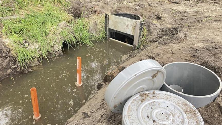 Regelbare stuw op een perceelsgracht. Stroomopwaarts van de stuw is de waterstand in de gracht hoger dan stroomafwaarts, het overtollige water stroomt nog steeds weg.